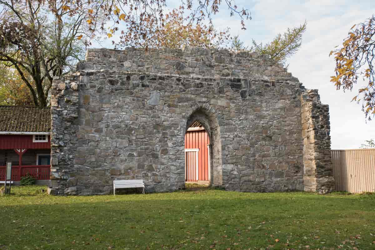 Fotografi av ruinen av klosteret. Ein tjukk steinvegg med døråpning, men ingen dør eller tak.