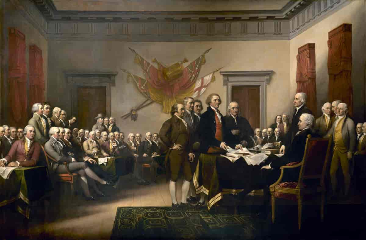 Maleri som forestiller undertegningen av uavhengighetserklæringen. En stor sal med mange menn. De fleste sitter på rekke til venstre i bildet. Til høyre i bildet er en mindre gruppe menn samlet rundt et bord med papirer.