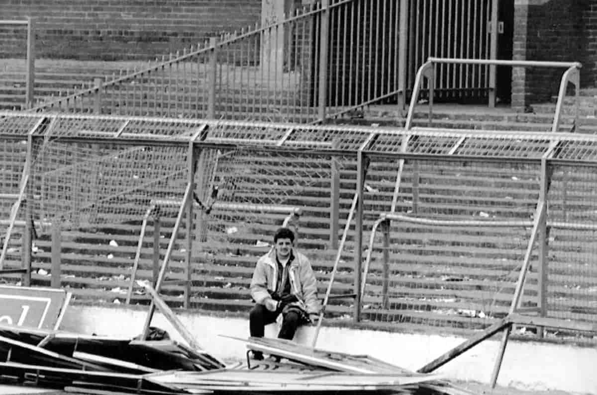 Mann sitter alene på en rasert, gammelt fotballtribune.