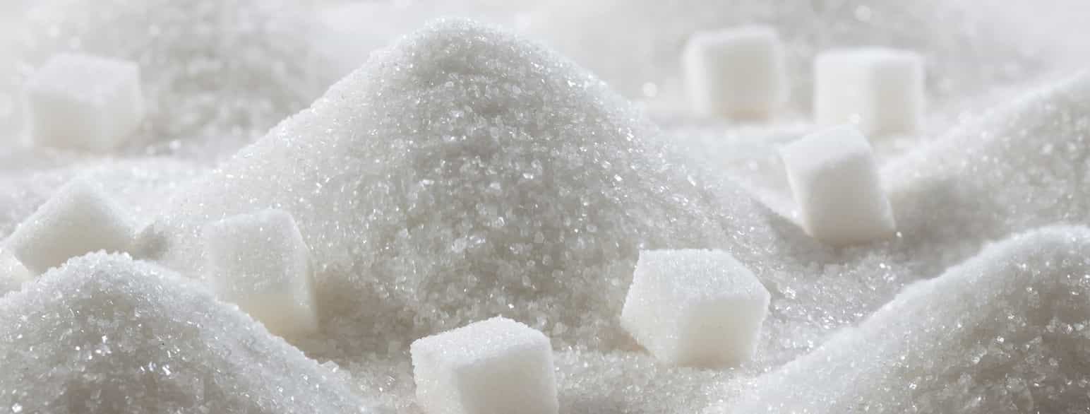 Foto av sukker i små hauger med sukkerbiter rundt omkring