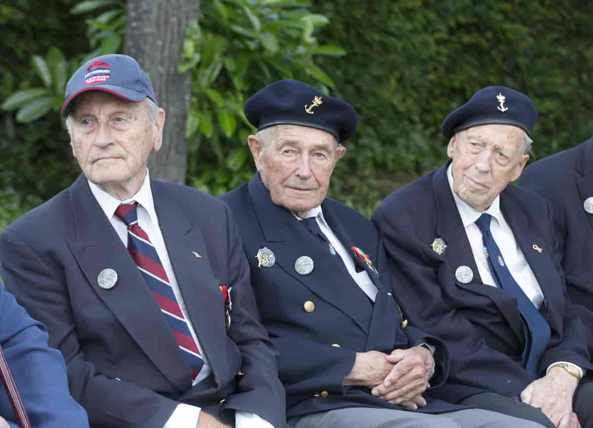 Bilde av tre krigsveteraner, tre eldre menn kledd i dress og med medaljer på jakkeslaget.  
