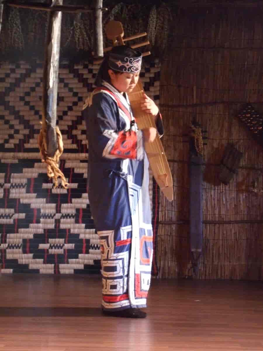 Fotografi av aino-kvinne som spiller et tradisjonelt instrument