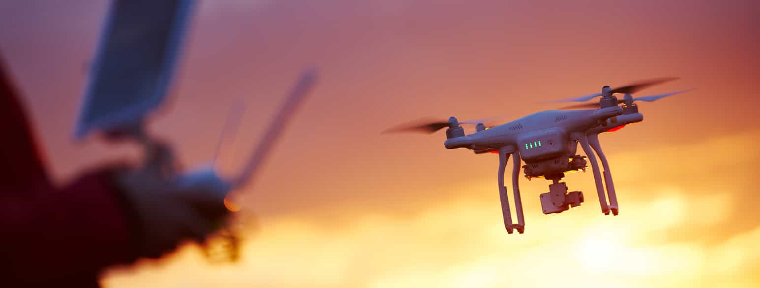 En drone som flyt i solnedgang. Til venstre i bildet er det en skygge av den som styrer dronen.