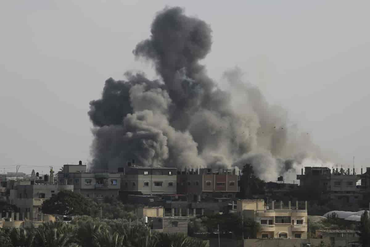 Foto av bygninger i Gaza, svart og grå røyk velter opp.
