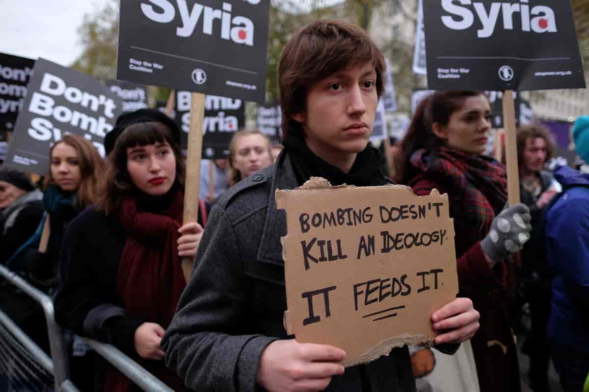 Demonstrant holder opp en papp-bit hvor det står "Bombing doesn't kill an ideology, it feeds it"