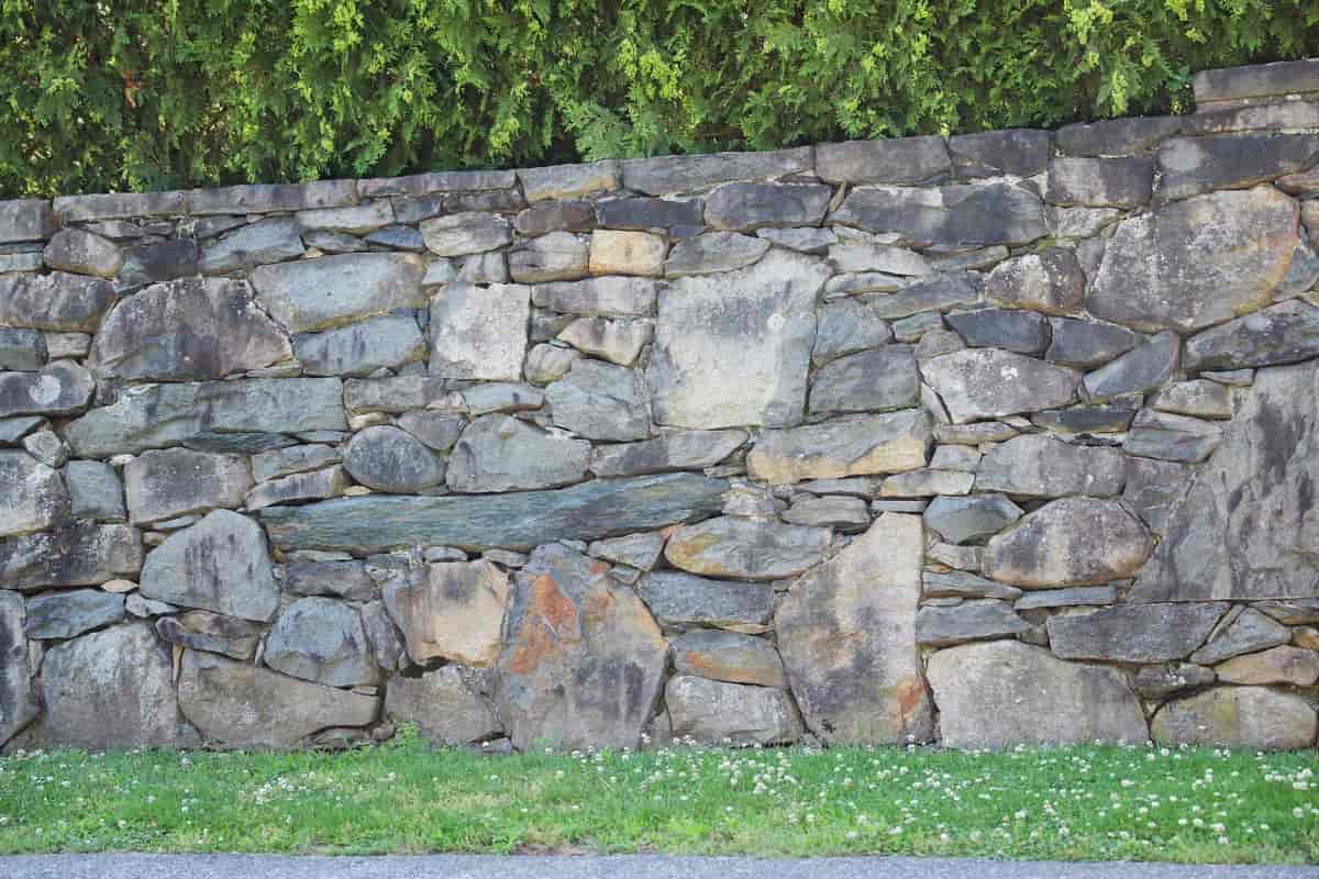 En bit av et steingjerde bygget i grå stein. Steinen har ulik størrelse, men er satt tett sammen som et puslespill.