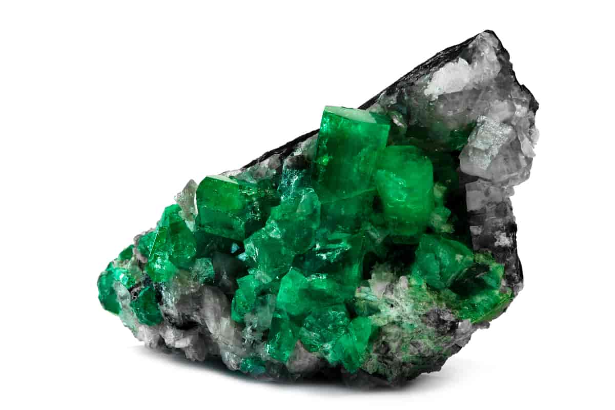 En stein med grønne smaragder i rå form. Smaragder står som små søyler opp av den grå steinen.