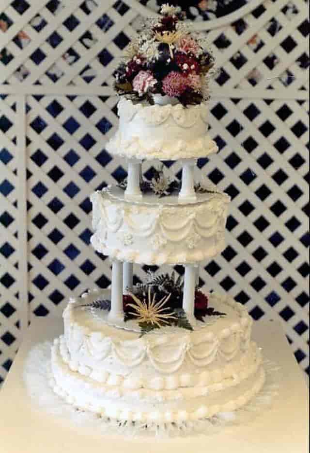 Kake i tre etasjer, med forseggjort hvit glasur og dekorert med blomster