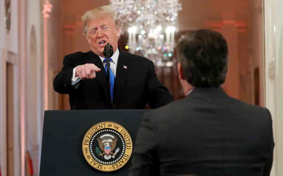 Donald Trump på talerstolen i Det hvite hus. Han peker mot en mann man ser bakfra