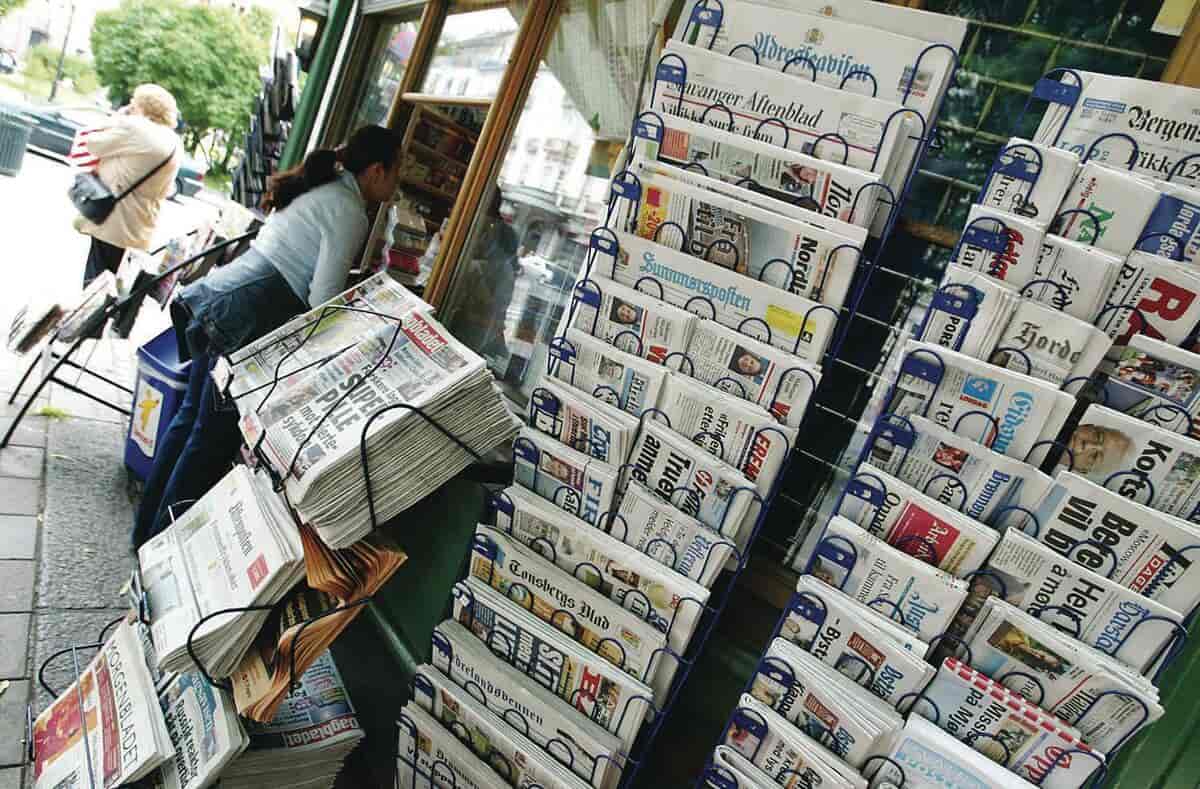 En aviskiosk med mange aviser utenfor i avisholdere.
