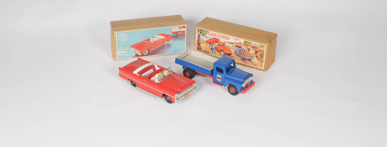 To lekebiler fra R.W. Bakke Finmekanisk verksted med tilhørende esker: en rød kabriolet og en blå lastebil.
