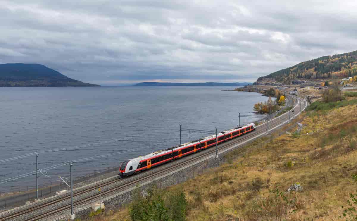 Foto av tog på vei langs Mjøsa.