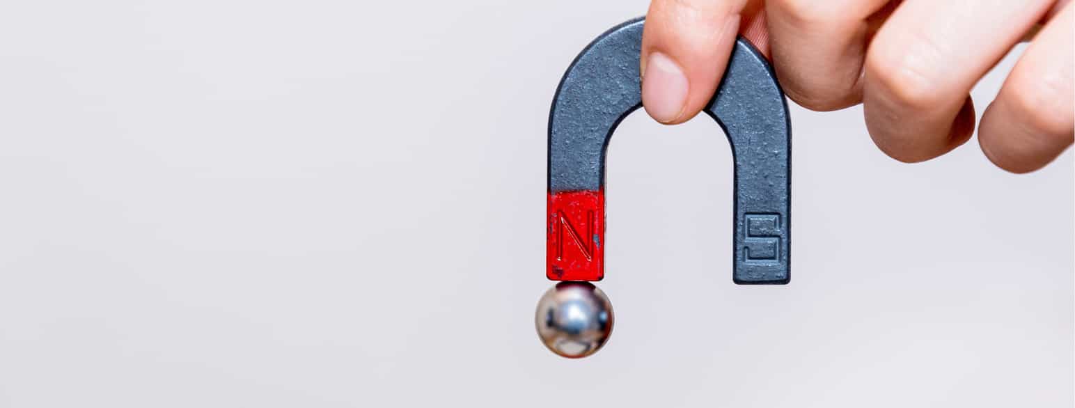 En magnet formet som en hestesko. Den er 2/3 blå og 1/3 rød. I enden av den røde delen er den en rund kule av metall som ser ut som jern.