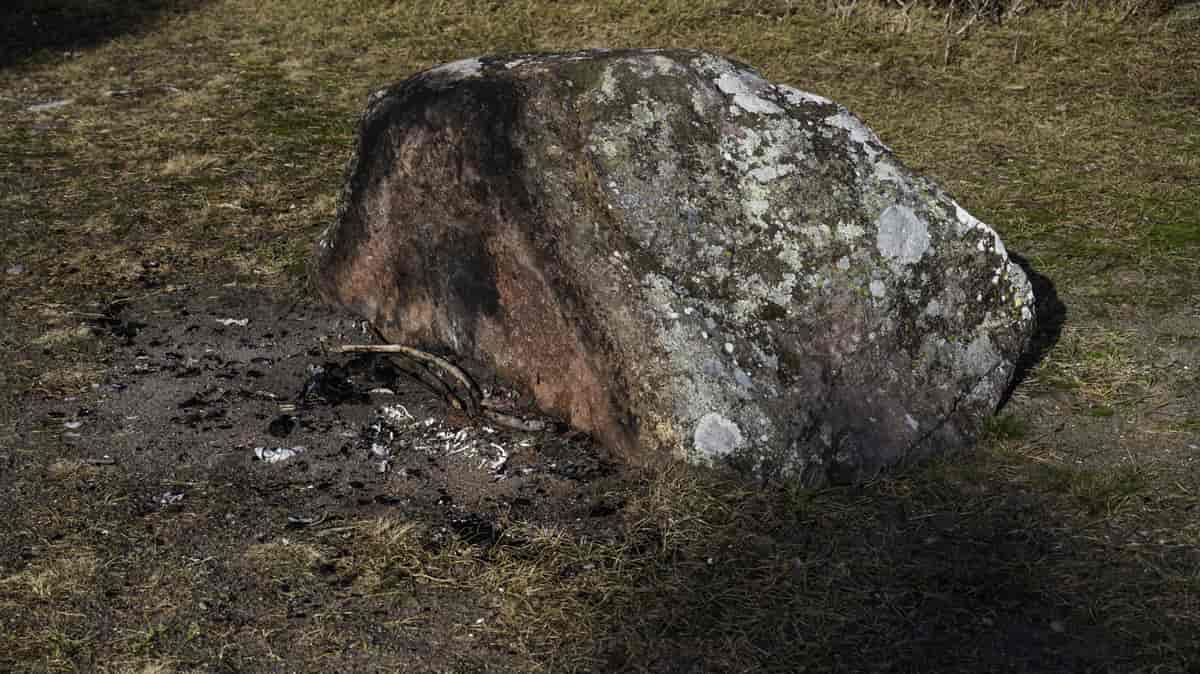 Foto av en bålplass som ligger opp mot en stein.