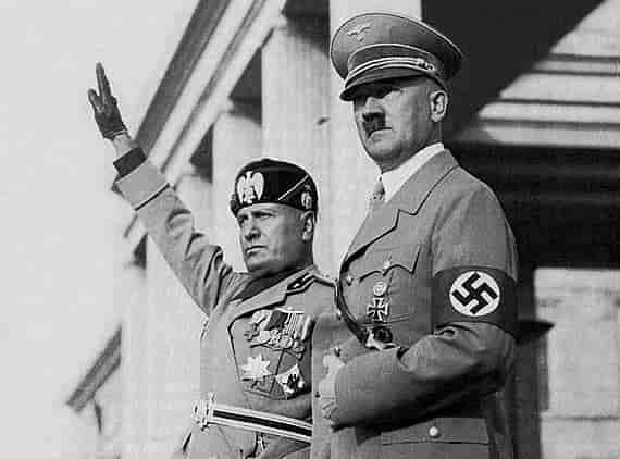 Svart-hvitt foto av Mussolini og Hitler i ulike uniformer. Mussolini (til venstre) holder høyre arm og hånd rett opp i lufta som en hilsen. I bakgrunnen er det en bygning med høye søyler.