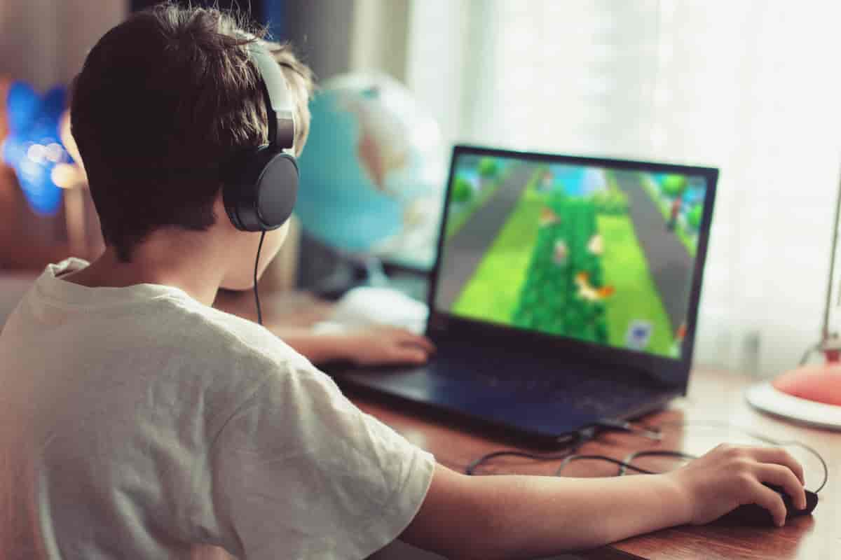 En gutt som sitter foran en datamaskin og spiller et spill.