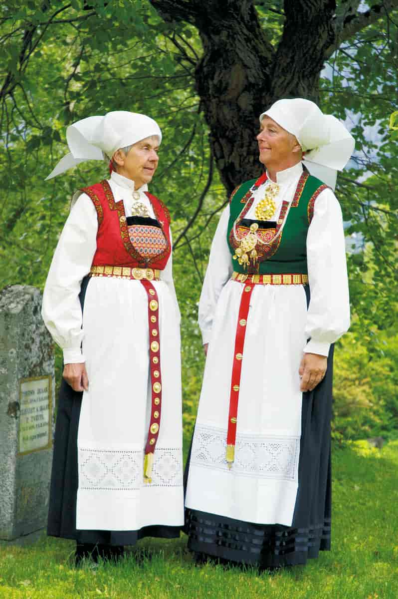 Foto av to kvinner i bunad. Bunadene har langt skjørt, vest og perlebroderi, og hvit skjorte. 