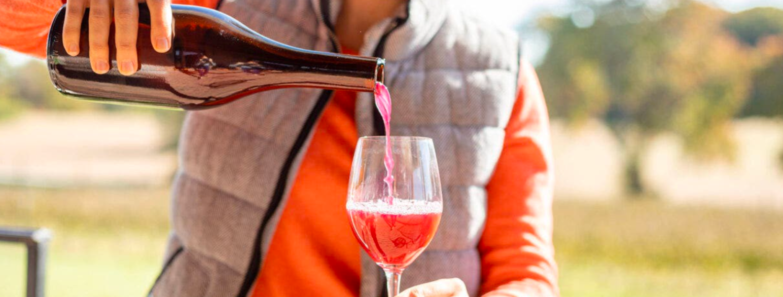 Foto av lys, rød vin som blir helt oppi et vinglass med stett.