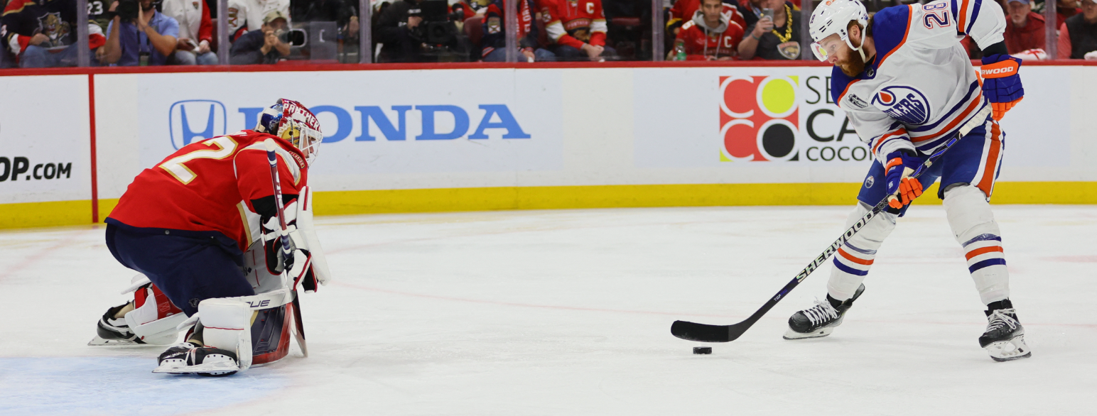 IShockeyspiller fører pucken på isen mot en målvakt som dekker målet