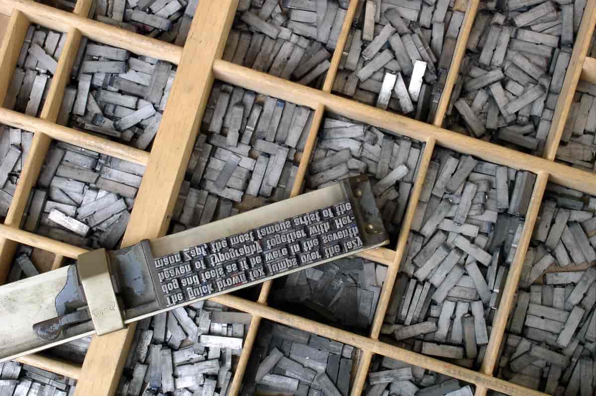 Typografisk settekasse og løse skrifttyper plassert i vinkelhake