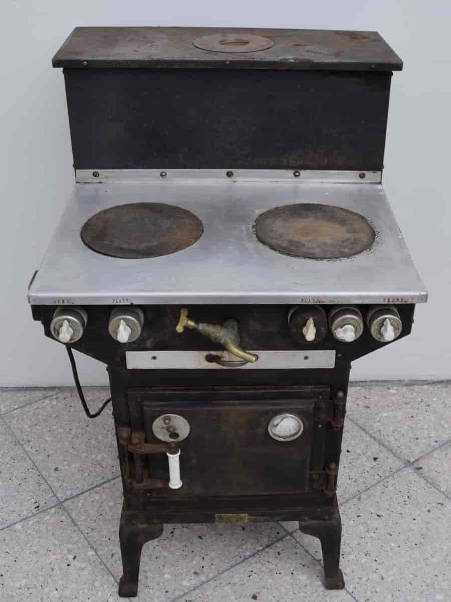Elektrisk komfyr med to plater, stekeovn og vanntank bak. Per Flølos patent av 1926