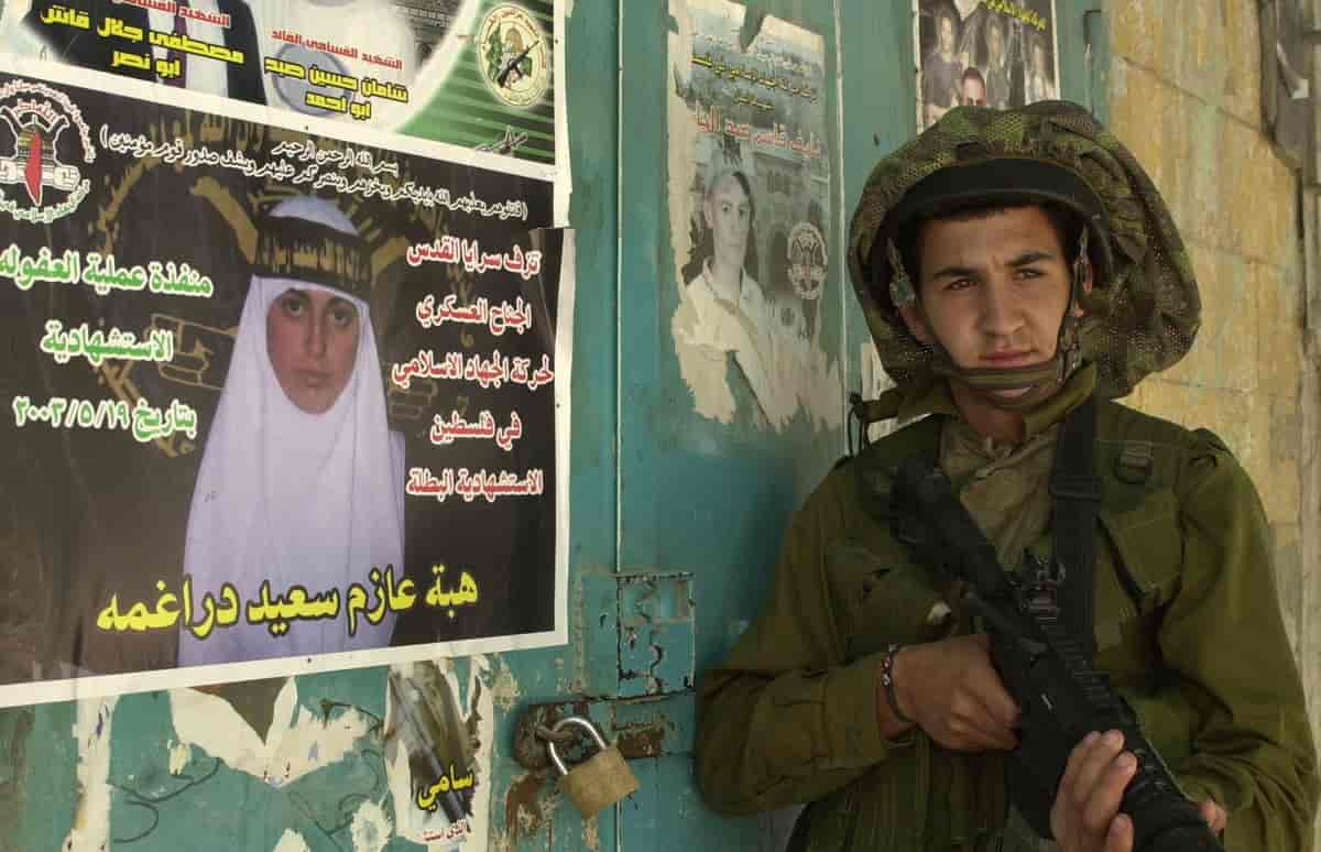 IDF soldat står foran palestinske martyrplakater