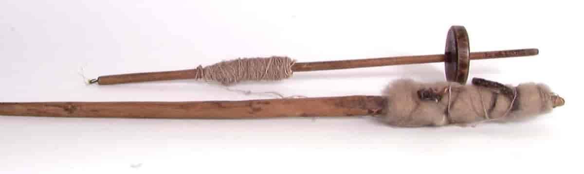 Øverst en tein med spunnet garn, under en håndrokk med ull.  Gjenstandene kommer fra Jølster i Sogn og Fjordane